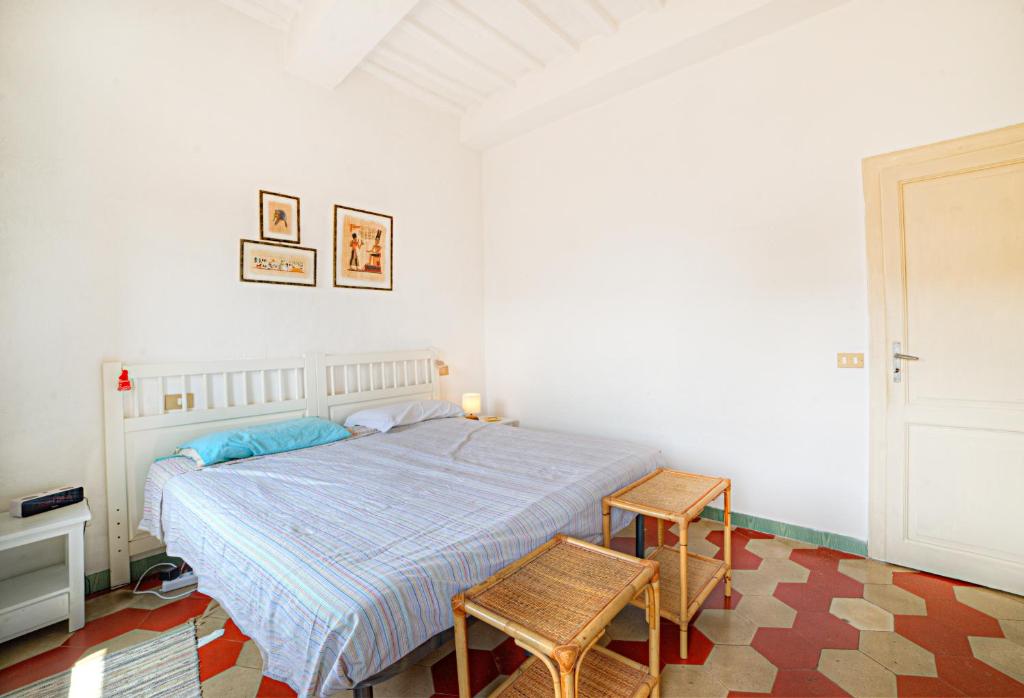 a white bedroom with a bed and two chairs at La casa di Fa' in Siena