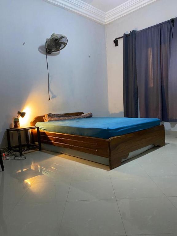 een slaapkamer met een bed met blauwe lakens en een ventilator bij CHAMBRE DHOTE SILLA in Mbour