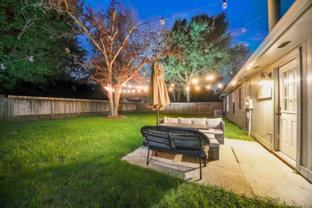 a patio with a couch and an umbrella at IAH Place: 4 bed, patio-sleeps 8+ in Humble