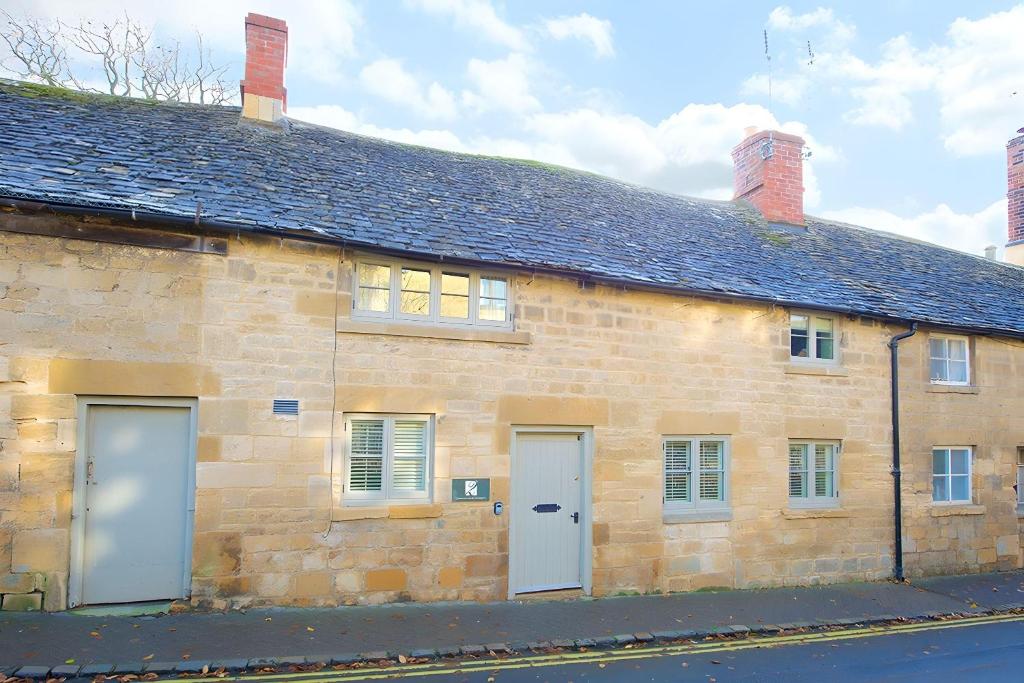 um edifício de pedra com duas portas brancas e um telhado em Cidermill Cottage em Chipping Campden