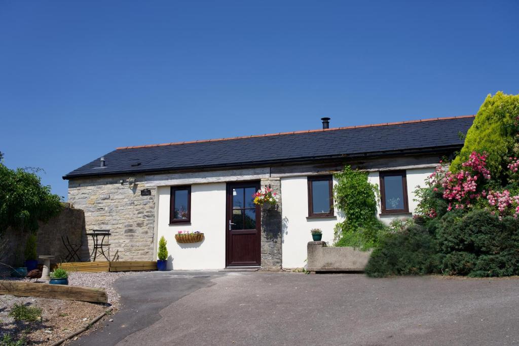 a white cottage with a black roof and a driveway at The Old Forge in Somerton