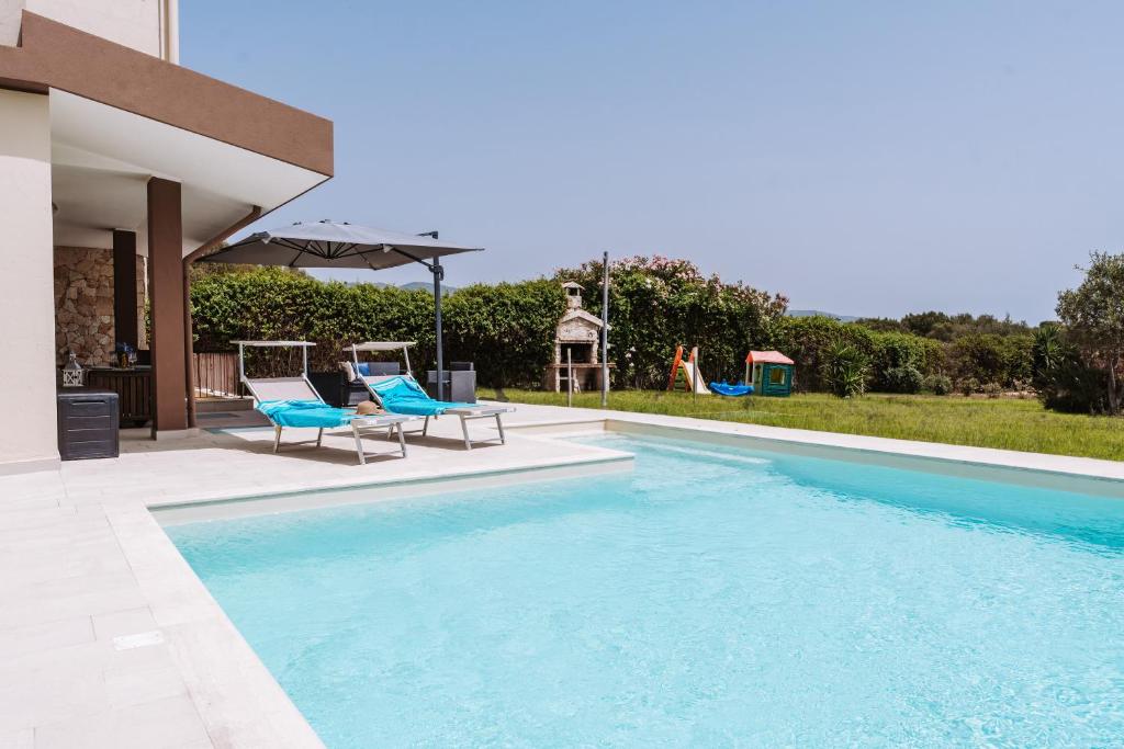 una piscina con due sedie e un ombrellone di Villa delle Viole a Quartu SantʼElena