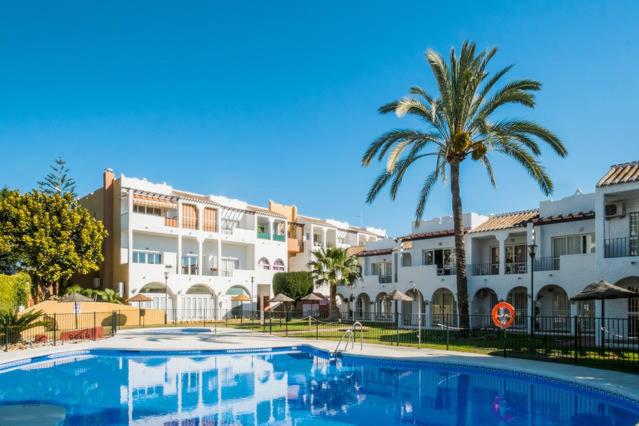 a swimming pool with a palm tree and buildings at Apartamento Rio Marinas Nerja 46 in Nerja