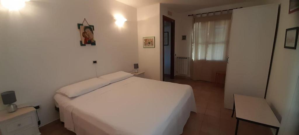 a white bedroom with a white bed and a table at Casa Vacanze La Rosa e L'Ulivo in Faiti