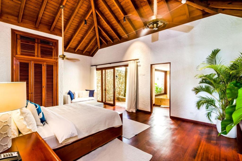 een slaapkamer met een bed in een kamer met houten plafonds bij Sunny Vacation Villa No 39 in San Rafael del Yuma