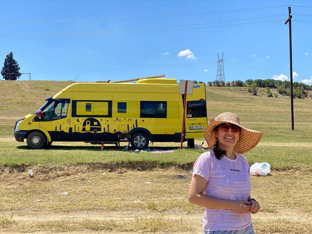 a woman in a straw hat standing in front of a yellow van at best camper van in tbilisi in Tbilisi City