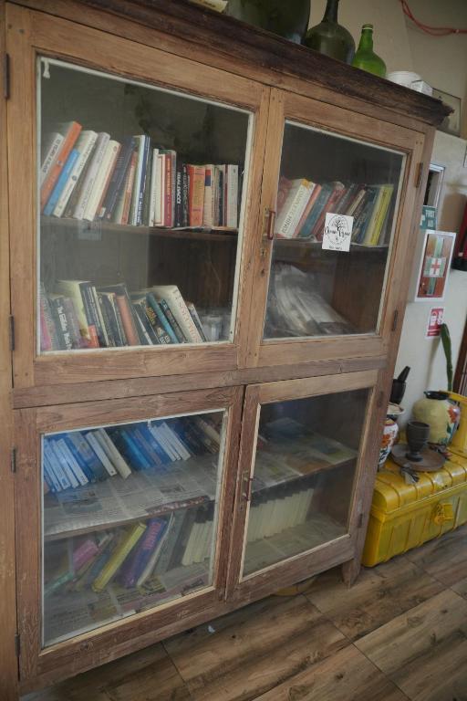 a wooden cabinet with glass doors filled with books at Dream Vision Guest House in Diu