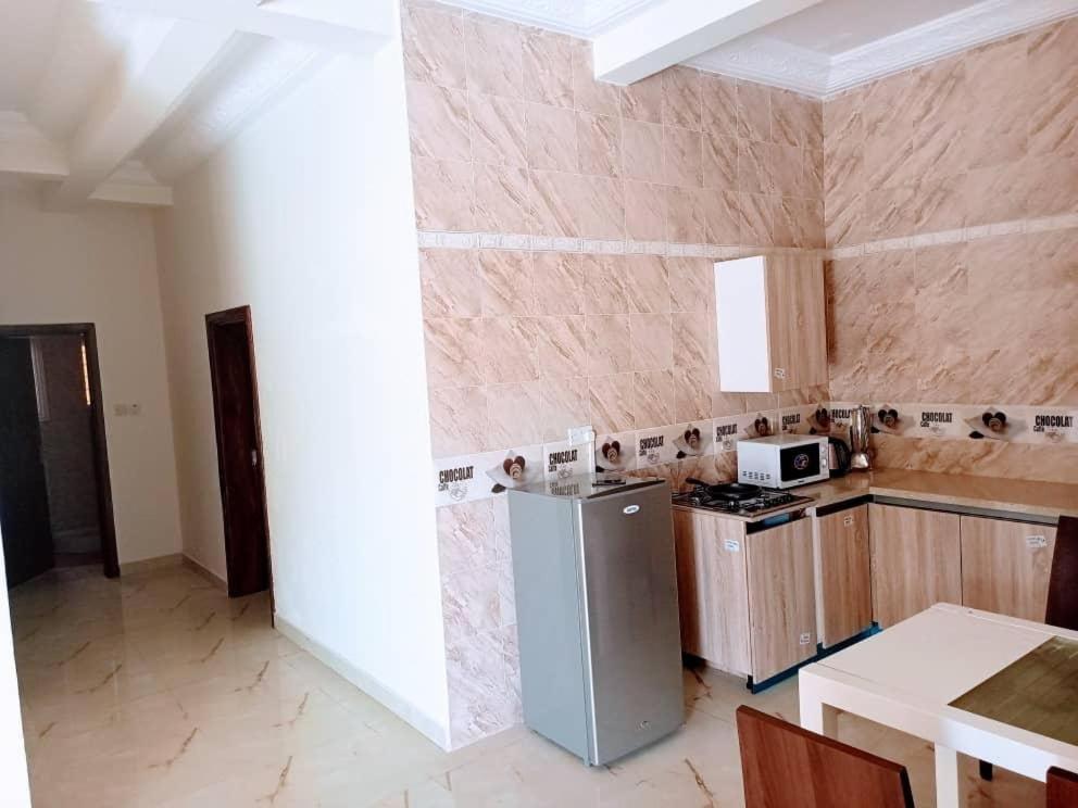 a kitchen with a refrigerator and a counter top at Akkwa 2 Suites in Kololi