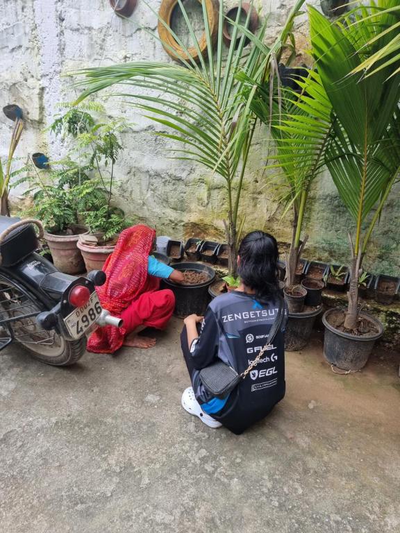 two people sitting on the ground looking at plants at Dream Vision Guest House in Diu