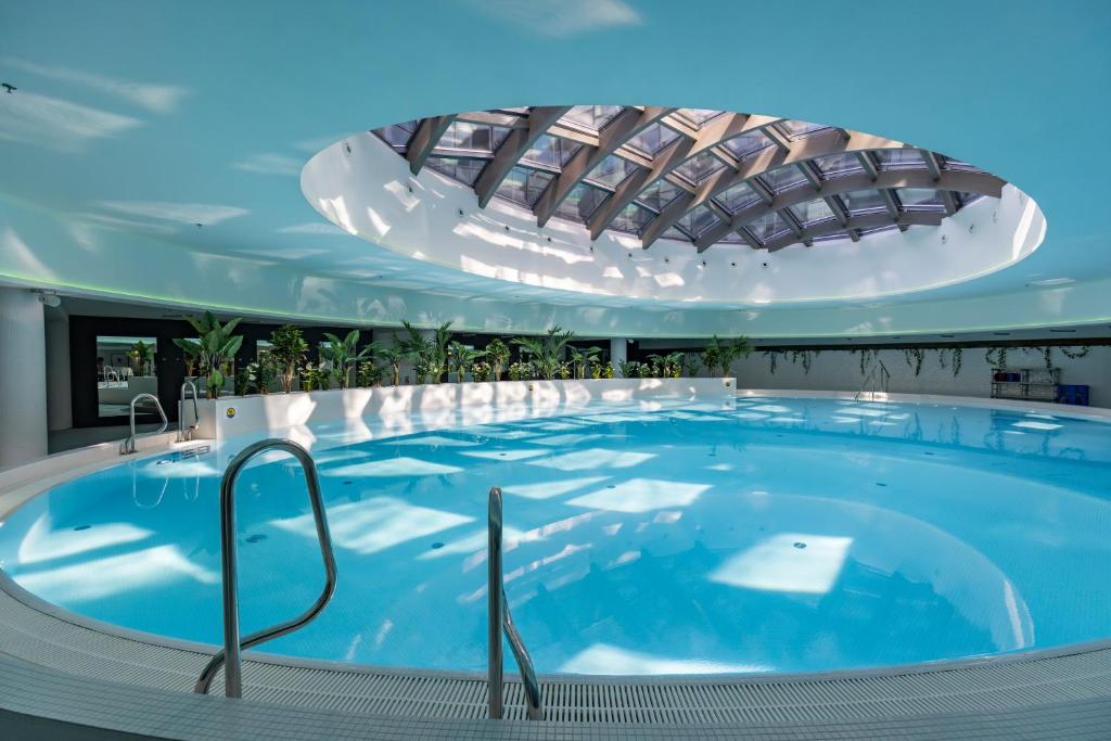 a large swimming pool in a building with a ceiling at Kaleo apartments - Hanza Tower in Szczecin