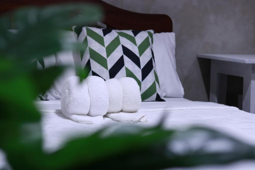 1 cama con almohadas blancas y almohada verde y blanca en El Nido U Inn en El Nido