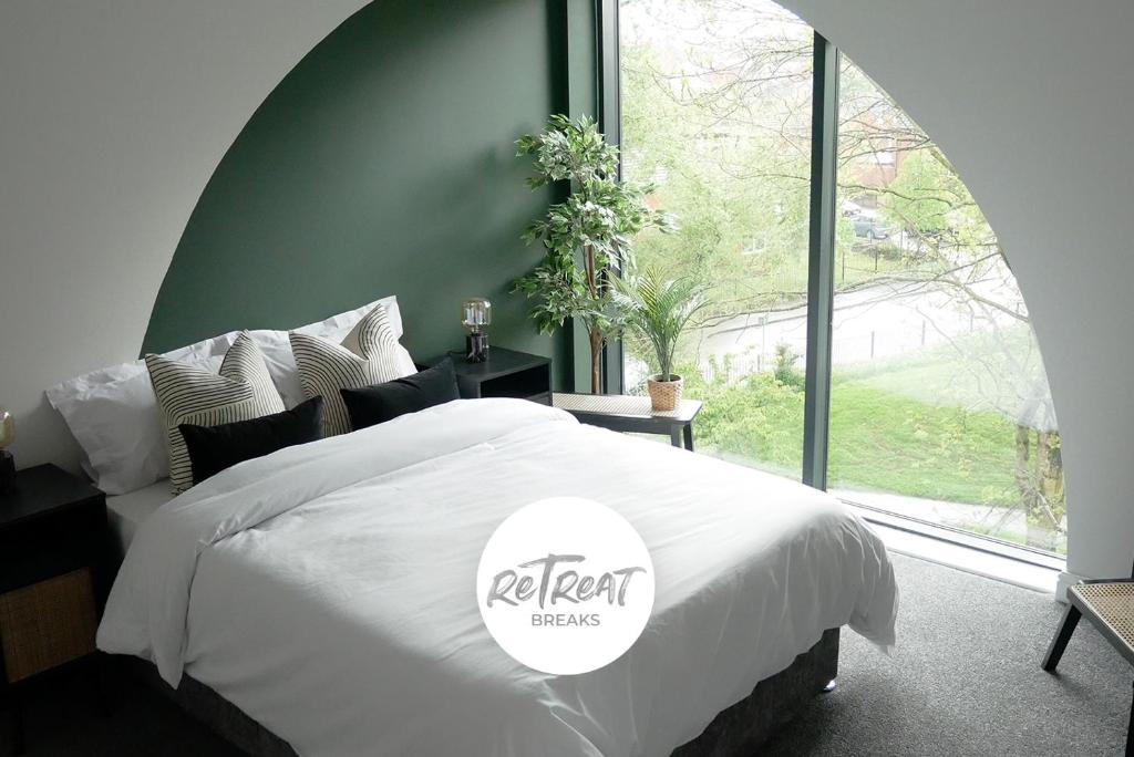 a bedroom with a white bed with a large window at ReTreat Breaks - 3 Bedroom Penthouse - Holbeck Leeds in Leeds
