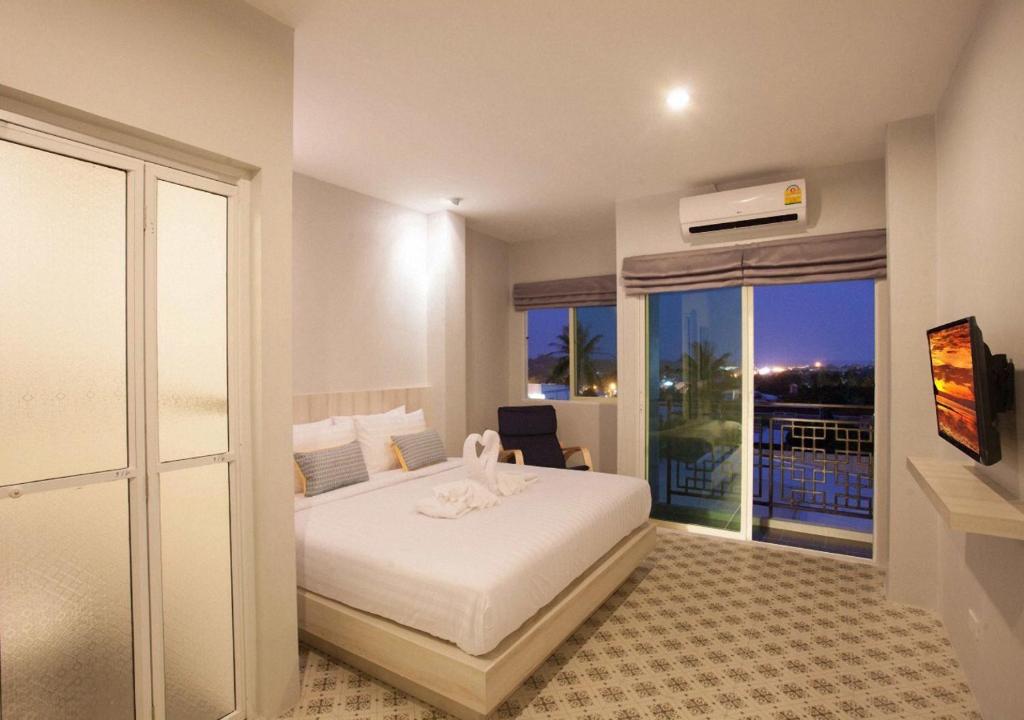 a bedroom with a white bed and a balcony at Nature Pine Phuket เนเชอร์ไพน์ภูเก็ต in Rawai Beach