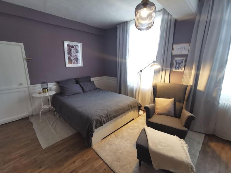um quarto com uma cama e uma cadeira em Le 1675_I - Confort et charme de l'ancien em Rouen