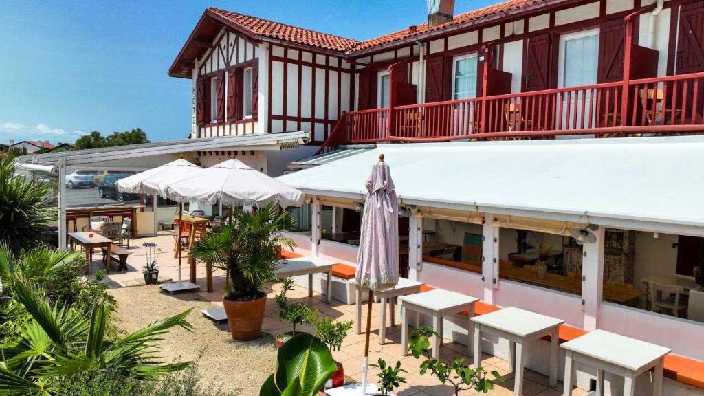 a hotel with tables and umbrellas in front of a building at La Maison Uhabia in Bidart