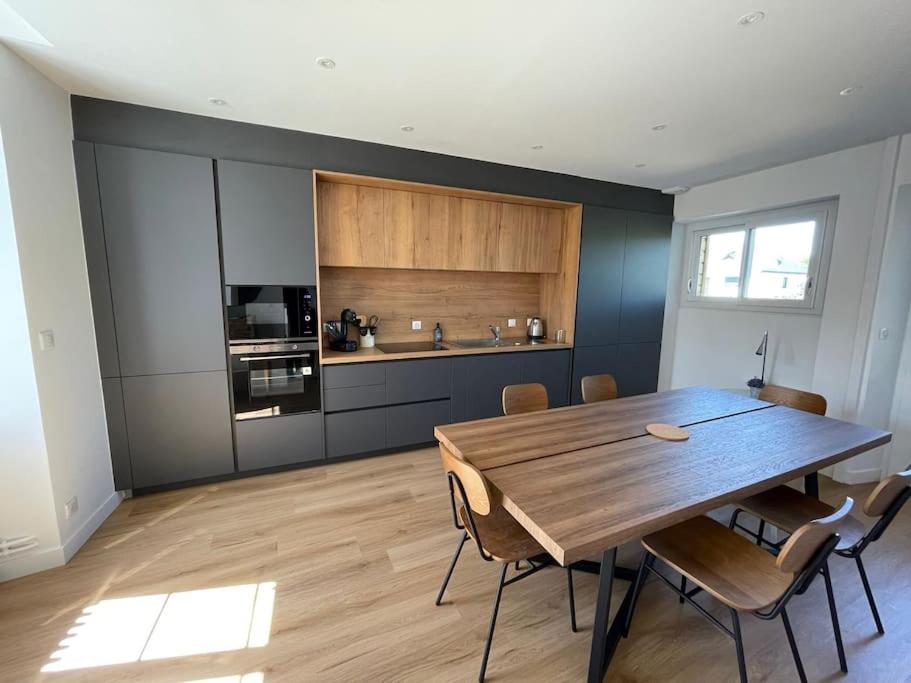 a dining room with a wooden table and a kitchen at LA DOUCE Saumuroise in Angers