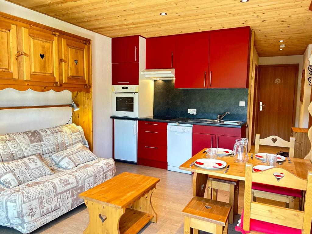 sala de estar con sofá y cocina con armarios rojos. en Studio Les Gets, 1 pièce, 4 personnes - FR-1-623-227 en Les Gets