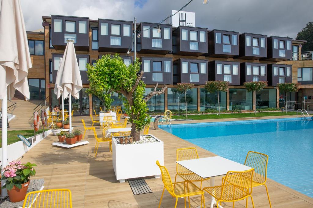 a hotel with tables and chairs next to a pool at Hotel Herbeira in Cedeira