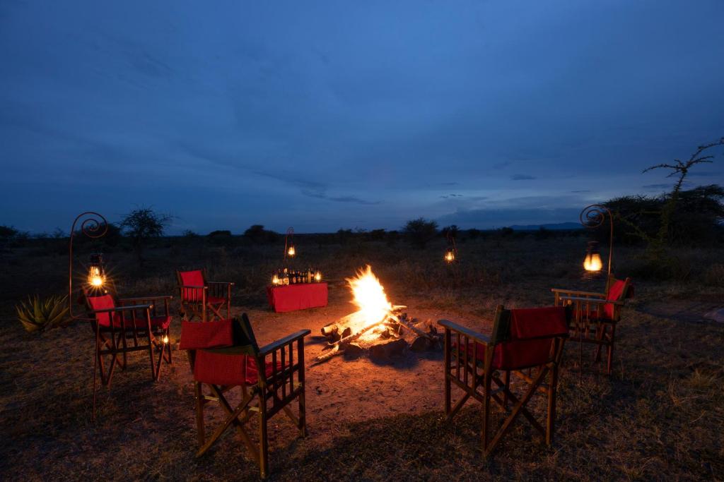 a group of chairs sitting around a fire at night at Africa Safari Serengeti Ikoma Camping in Serengeti