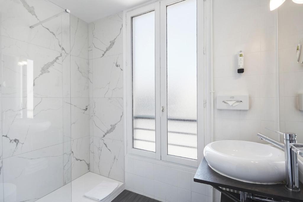 a white bathroom with a sink and a shower at Jardin de Villiers in Paris
