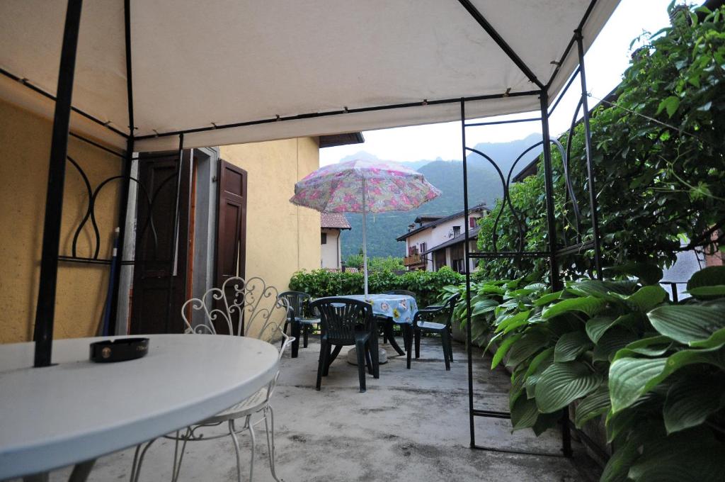 a patio with tables and chairs and an umbrella at Casa Anna in Ledro