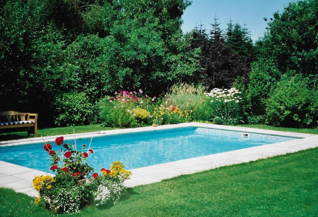 a swimming pool in a garden with flowers in the grass at Les 3 Fontaines in Verviers