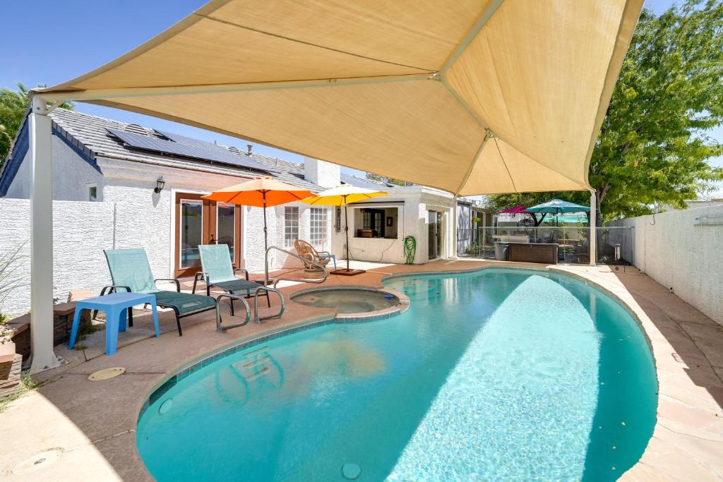 uma piscina com guarda-sol, cadeiras e mesas em Sunny Las Vegas Studio with Shared Pool and Backyard! em Las Vegas