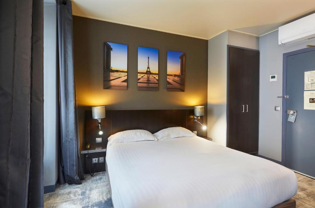 a bedroom with a large white bed with three paintings on the wall at Jardin de Villiers in Paris