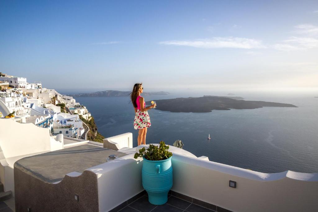 a woman standing on a ledge looking out over the ocean at Remvi Suites in Firostefani