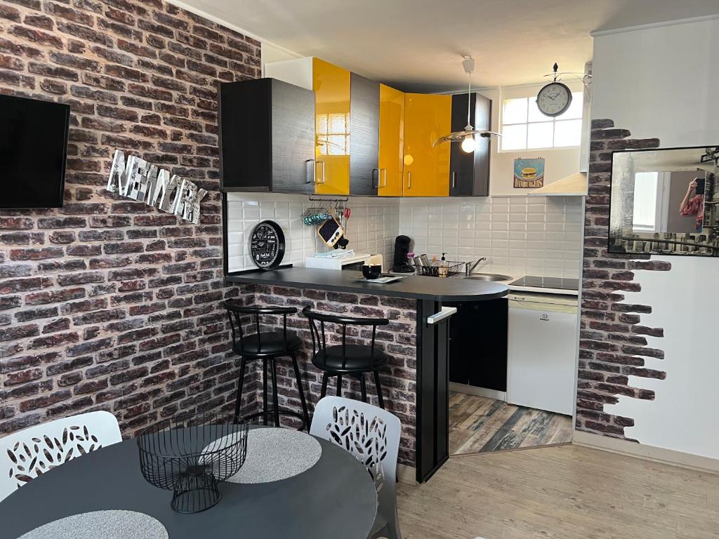 a kitchen with a brick wall and a counter with stools at Appartement 100 m de la plage in Saint-Palais-sur-Mer