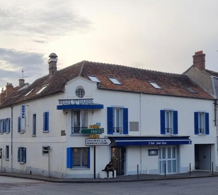 a large white building with blue shutters on a street at Hôtel Sainte-Barbe in Guignes-Rabutin