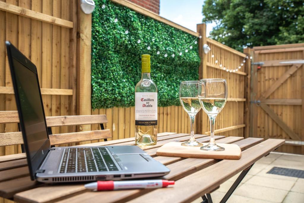 un ordenador portátil en una mesa con una botella de vino y copas en 出入平安 BUSINESS OR PLEASURE! NEW Southampton 'City Vibes' # Super Central & Stylish Apartment with Outside Space! for 1-4 Guests BOOK YOUR CITY BREAK or PRE-CRUISE STAY! CLOSE TO MAYFLOWER THEATRE, UNIVERSITIES, CRUISE TERMINALS, HOSPITALS & SHOPS!, en Southampton