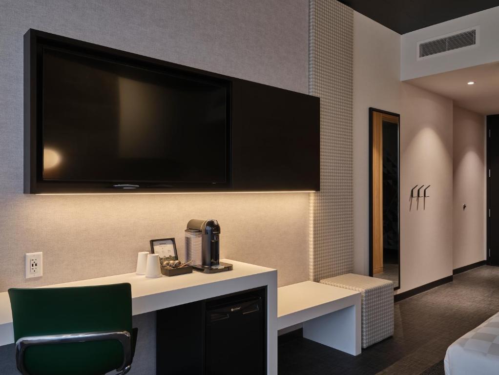 a room with a desk with a television on a wall at Alt Hotel Calgary University District in Calgary