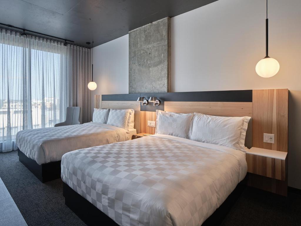 a hotel room with two beds and a window at Alt Hotel Calgary University District in Calgary