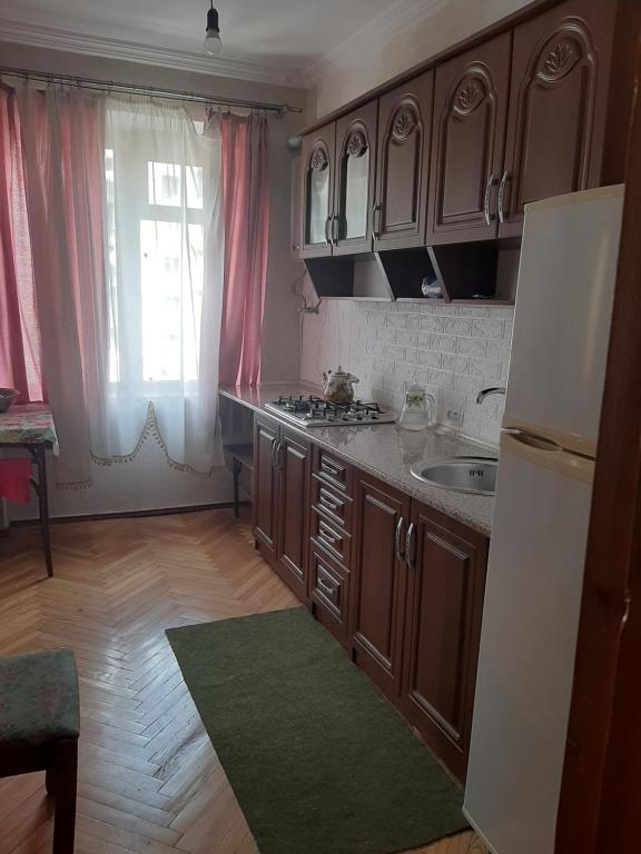una cucina con armadi marroni, lavandino e finestra di hotel a Chiatʼura