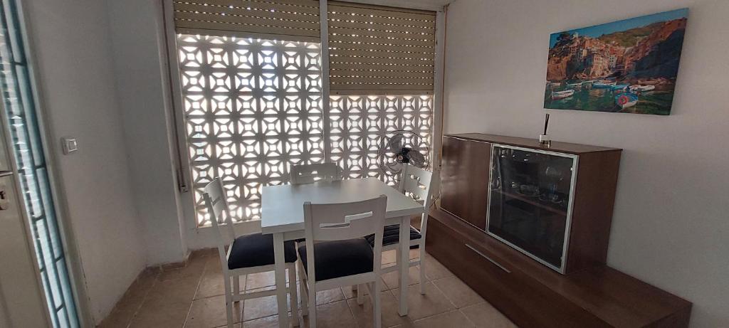 - une table et des chaises blanches dans une chambre avec fenêtre dans l'établissement Casita cerca del mar, à Playa de Gandia