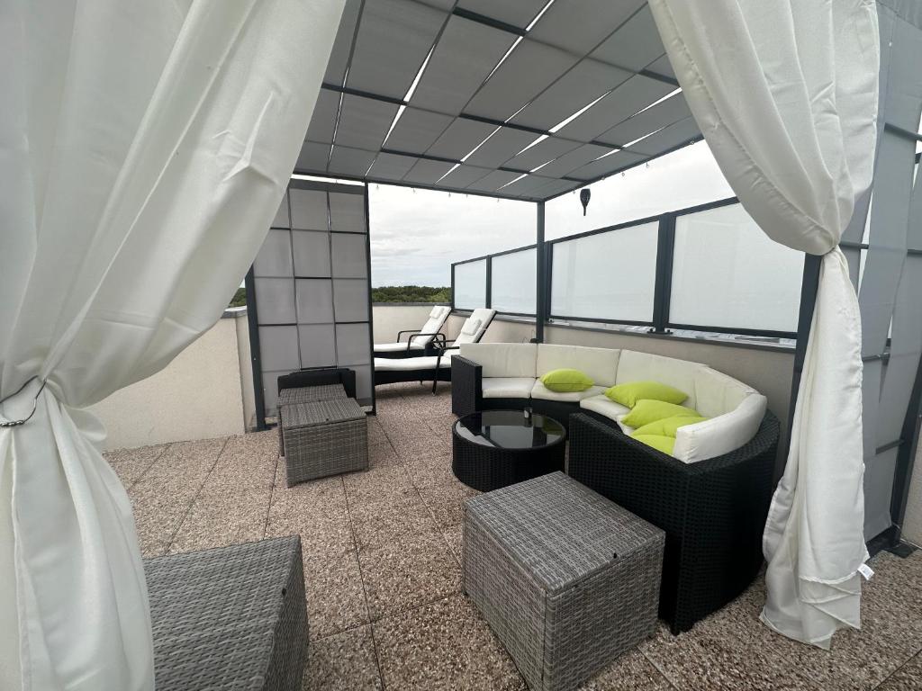 a balcony with a couch and chairs on a boat at PENTHOUSE Terrasse Jacuzzi 6 voyageurs in Le Blanc-Mesnil