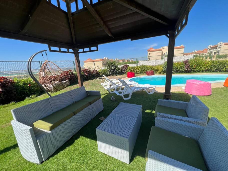 a patio with two chairs and a swing and a pool at استديو بحمام سباحه خاص 