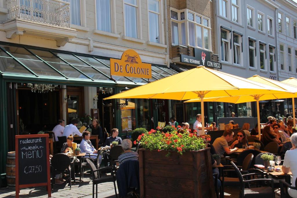a restaurant with tables and umbrellas on a sunny day at Stadshotel De Klok in Breda