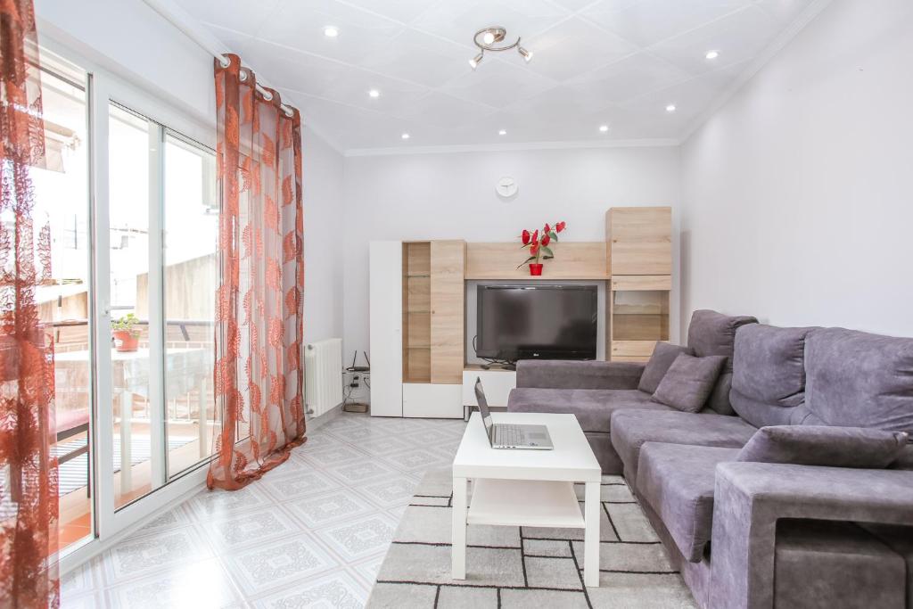 a living room with a couch and a tv at Central Beach Modernist Apartment in Lloret de Mar