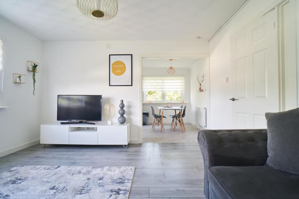 a living room with a couch and a flat screen tv at Woodside Apartment in Coatbridge