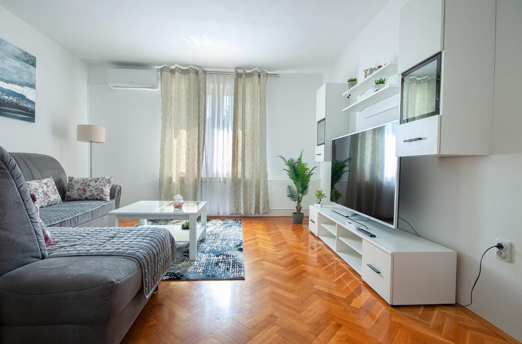 Apartman Plitvice Happy Home في بليتفيتْشكا ييزيرا: غرفة معيشة مع أريكة وتلفزيون