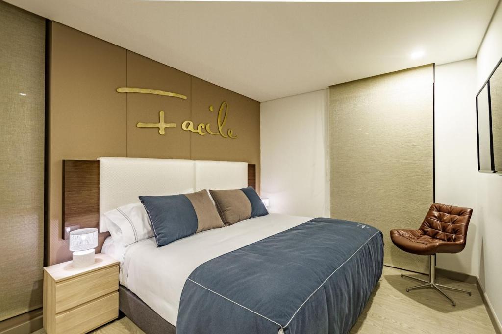 a bedroom with a large bed and a chair at APARTAMENTOS FACILE in Bogotá