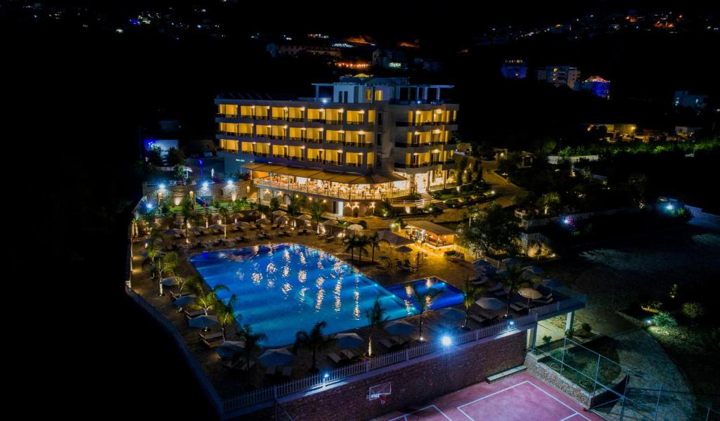 a view of a hotel with a pool at night at Elysium Hotel in Dhërmi
