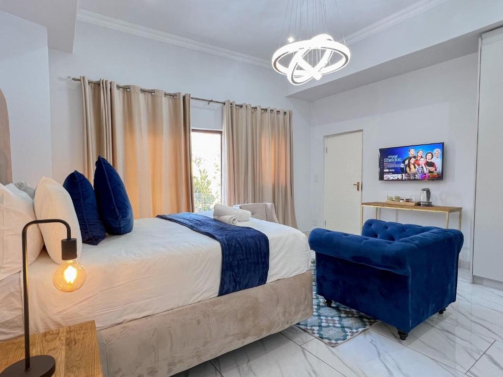 1 dormitorio con 1 cama grande y 1 silla azul en Amoris Guesthouse - In Randburg, en Johannesburgo