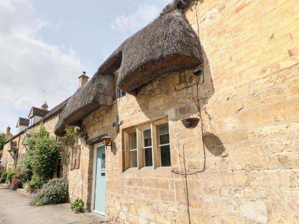 an old stone building with a thatched roof at Thatched Cottage in Chipping Campden