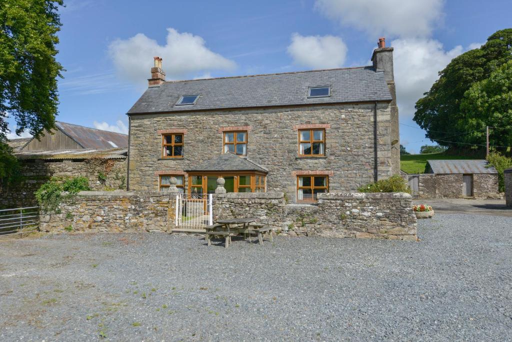 an old stone house with a bench in front of it at Haye Barton Farm in Liskeard