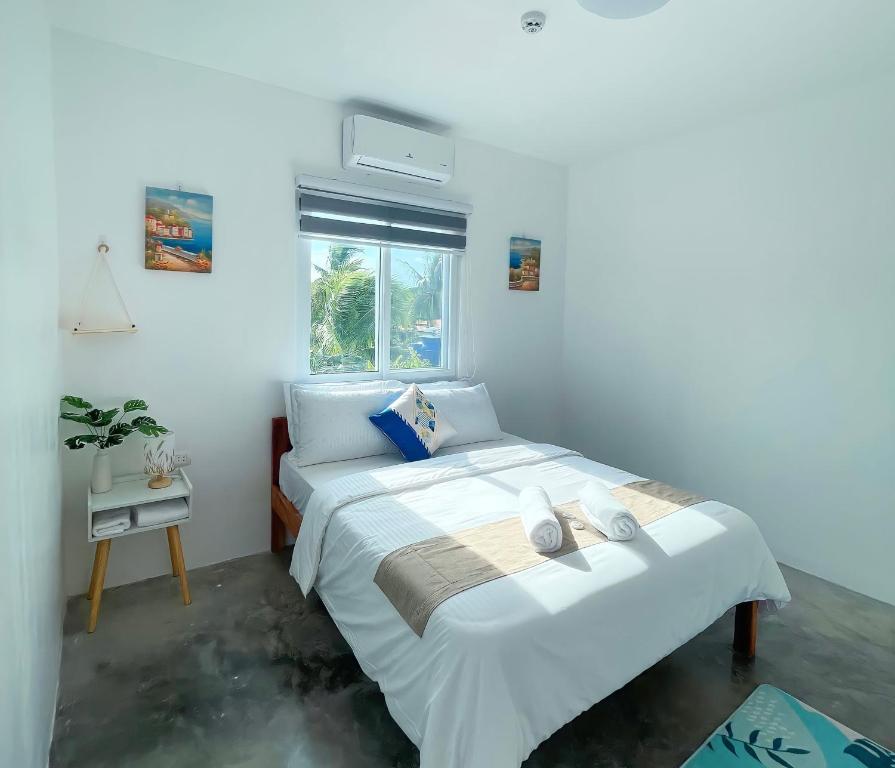 Un dormitorio con una gran cama blanca y una ventana en Sunset Paradise Moalboal, en Moalboal