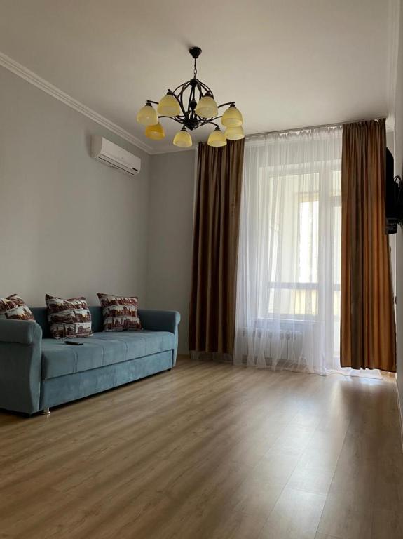 sala de estar con sofá azul y ventana en Красивая уютная двухкомнатная квартира в Экспо, en Taldykolʼ