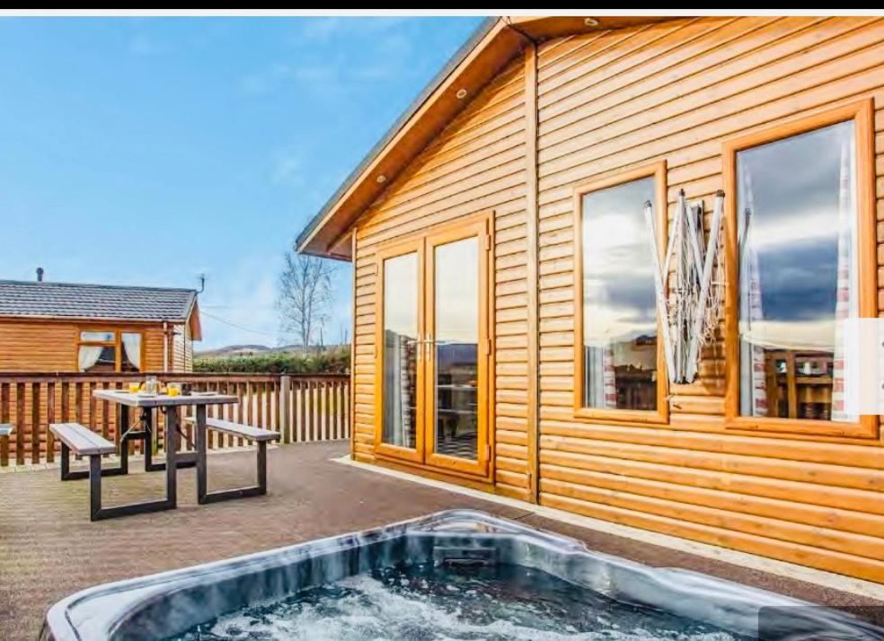 a wooden house with a hot tub in front of it at Clochnaben lodge, castle wood, strachan ab31 6NQ in Strachan